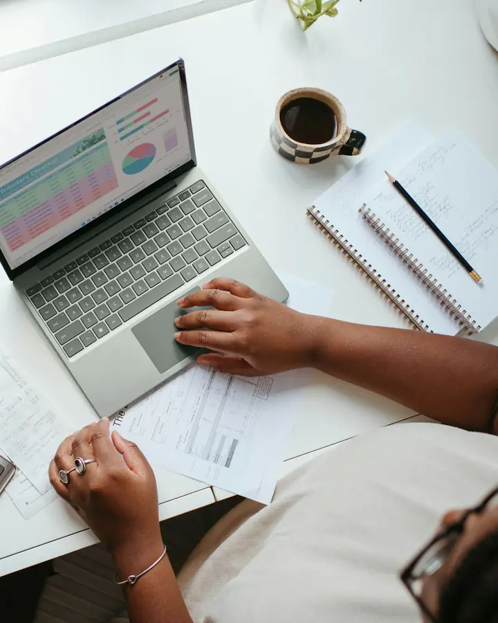 Iemand werkt aan een bureau met een laptop, een rekenmachine en facturen