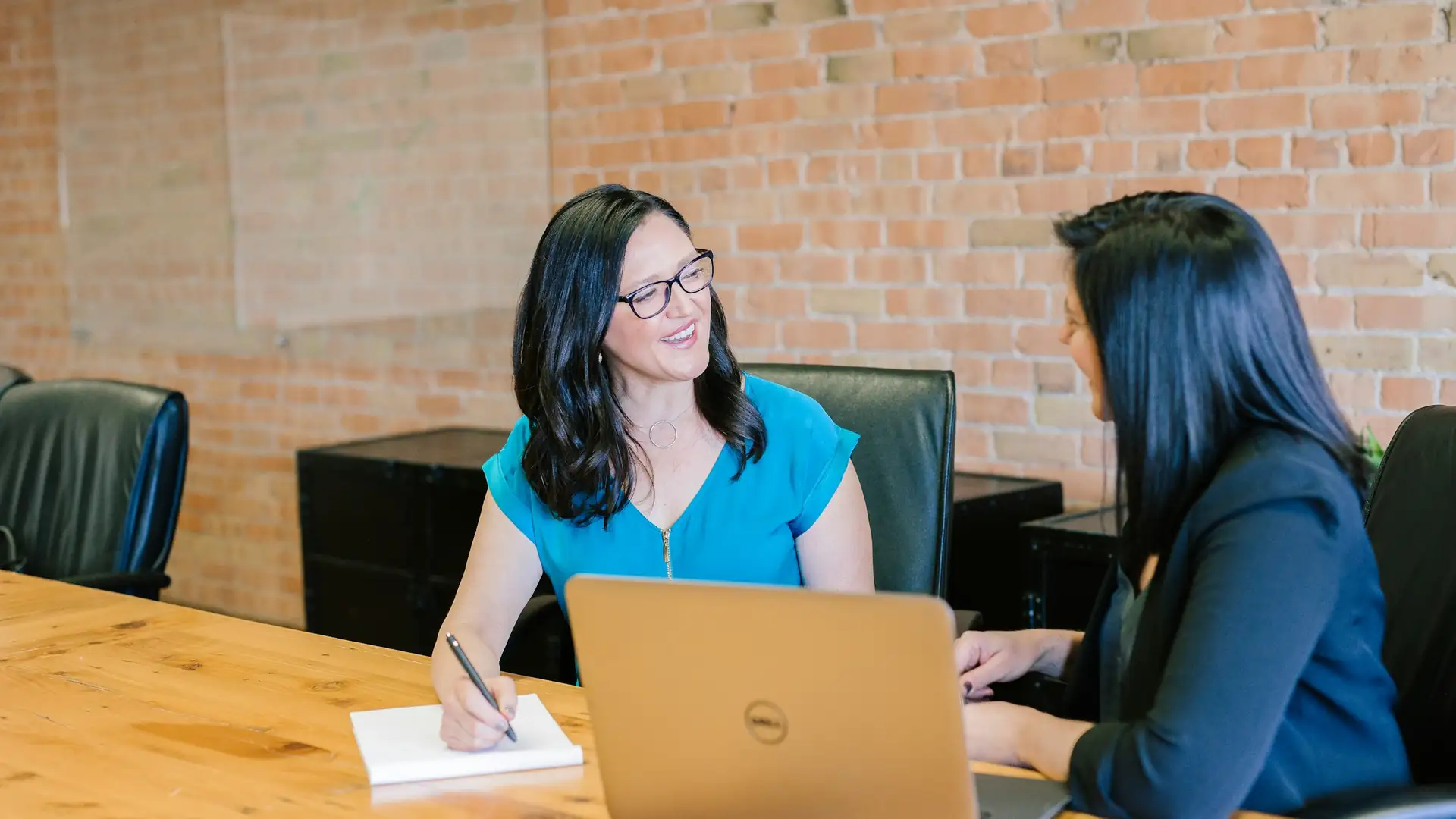 Twee collega's overleggen aan een tafel met een laptop