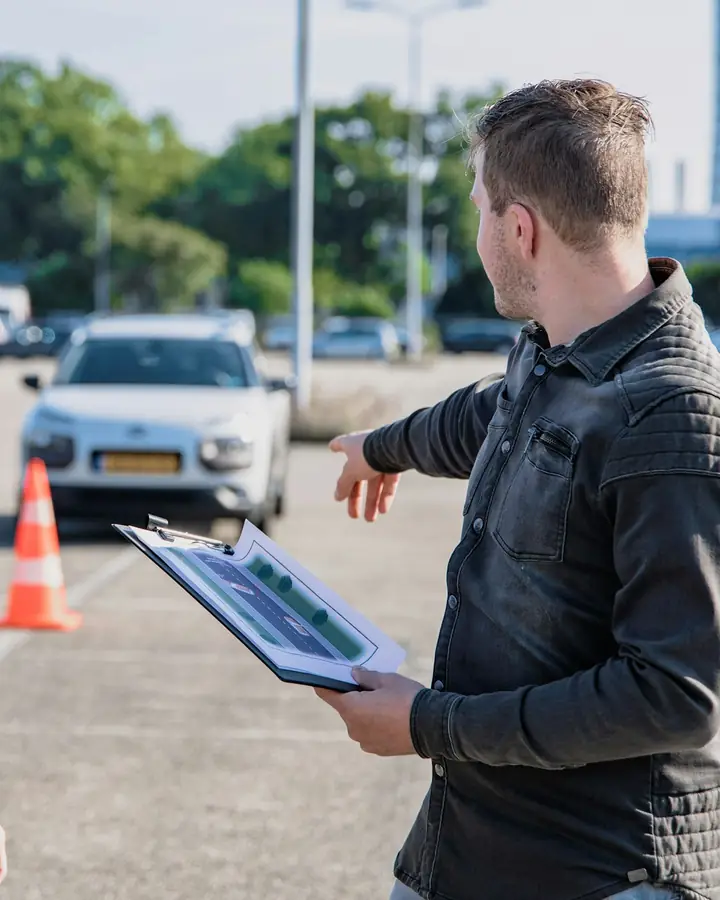 Een rij-instructeur legt iets uit naast de auto