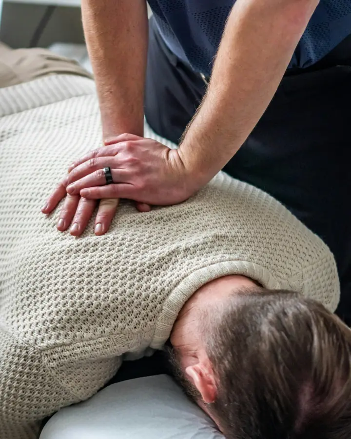 Een behandelaar masseert de rug van een patiënt
