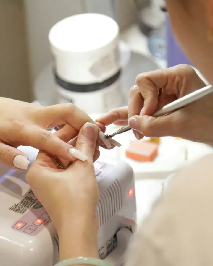 Een nagelstyliste werkt aan de nagels van een klant