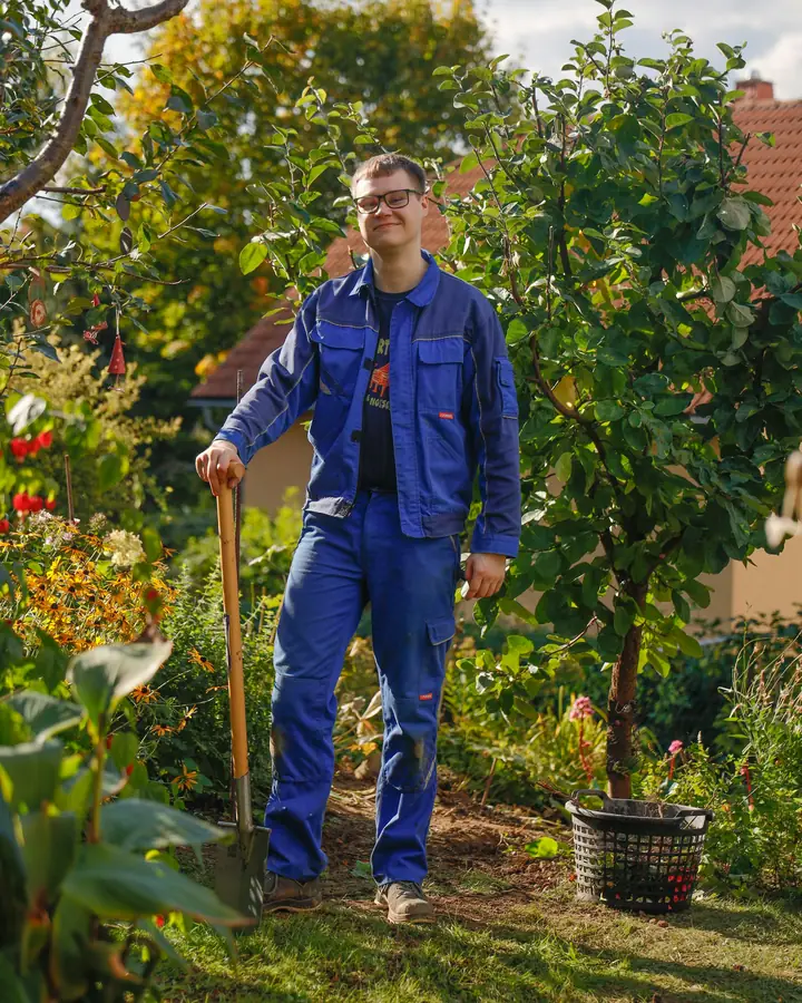 Een hovenier staat met een schep in een tuin
