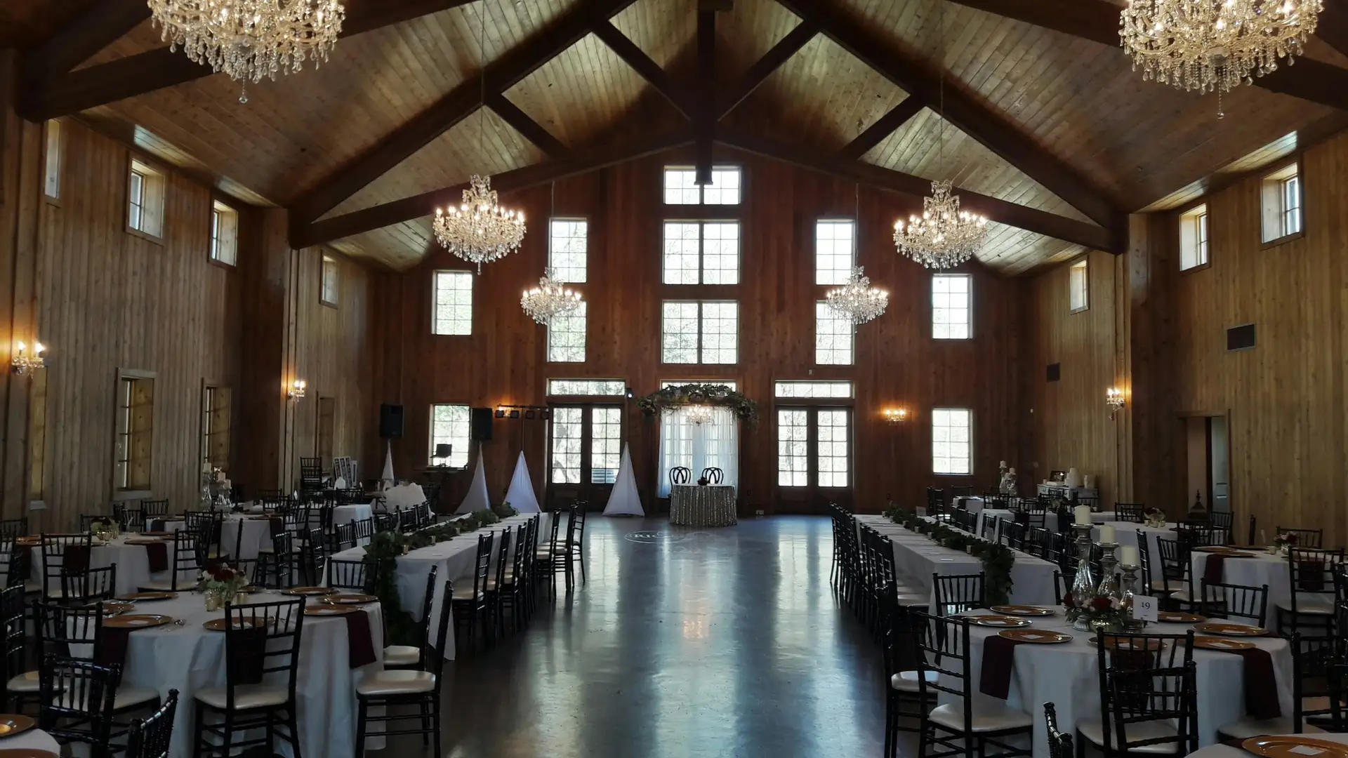 Een feestzaal met houten balken, kroonluchters en gedekte tafels