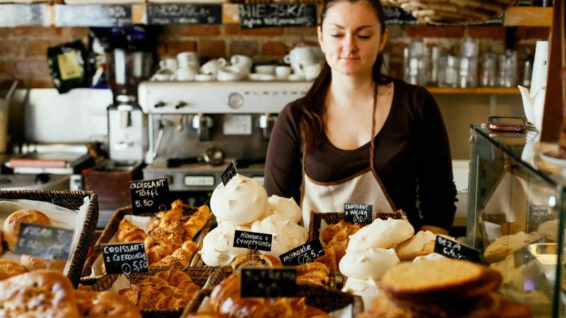 Een bakker achter een toonbank vol brood en koekjes