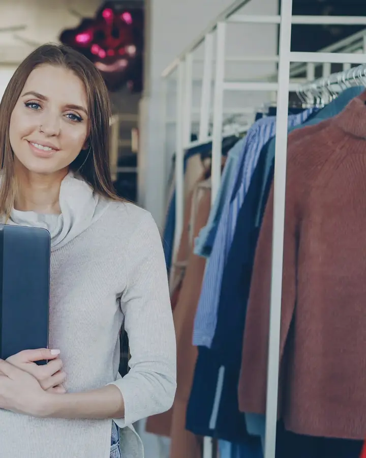 Een winkelier tussen de rekken van haar kledingzaak
